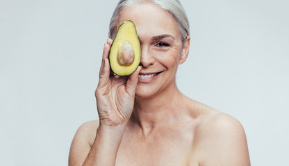 Senior woman with a half avocado