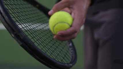 Close up of hands of male player holding racket and preparing to serve tennis ball. Tennis player...