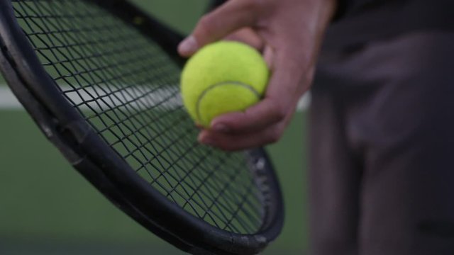 Close up of hands of male player holding racket and preparing to serve tennis ball. Tennis player ready to serve in the game.