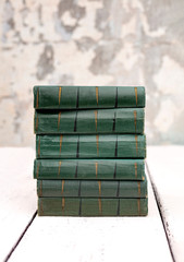 Stack of old ancient shabby books on a white wooden background.