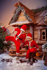 A group of four children in a Christmas hat and costumes with gifts near a fabulous house