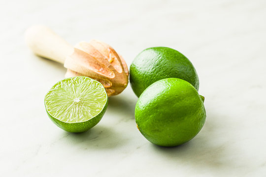 Wooden citrus squeezer and green lime.