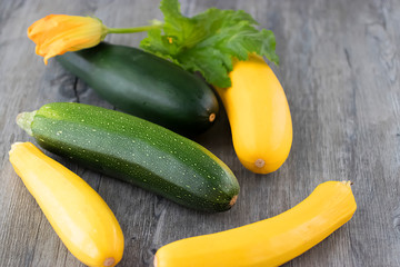 Yellow and green zucchini on a gray wooden background.