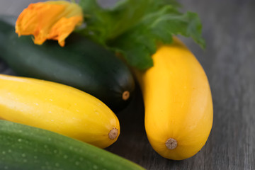 Yellow and green zucchini on a gray wooden background.