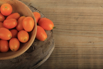 kumquat in wooden plate on wooden background. top view