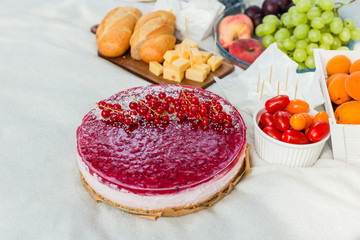 Picnic at the park on the grass: pie, tablecloth, fruits and vegetables, top view. Sweet tart with currant