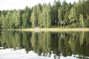 Panorama of the lake shore at sunset with reflection in the water. Finland .