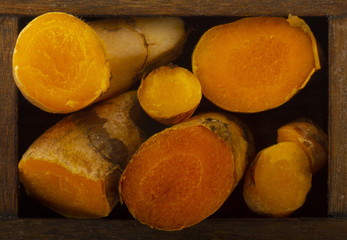 heap of turmeric slices  in wooden box