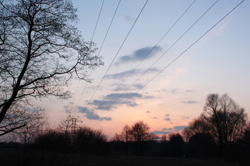 High voltage transmission towers silhouette on sunset and twilight sky.