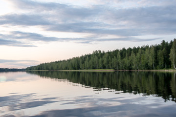 Panorama of the lake shore at sunset with reflection in the water. Finland .