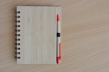 notebook with a cover with wooden texture, the pen on a wooden surface