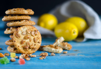 Round orange biscuits with colorful candied fruits and a slice of juicy orange lying on a wooden table