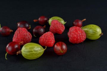 Fototapeta na wymiar Assorted berries on a black background. Juicy wild berries.