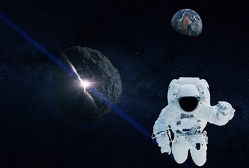 Fototapeta na wymiar The astronaut departs from Earth which the asteroid approaches. Elements of this image were furnished by NASA