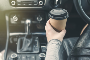 woman driving a car and holding paper cup of coffee