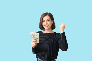 Happy young woman with money on color background