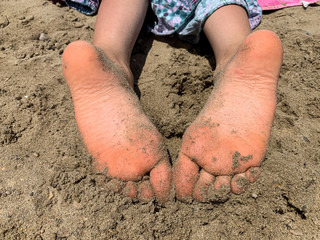 Sandy feet on a beach by the sea