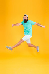 Fototapeta na wymiar Energetic and upbeat music for leisure. Energetic hipster jumping high on yellow background. Bearded man in mid air. Brutal guy enjoying energetic music. Active and energetic