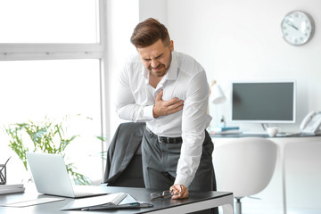 Young businessman having heart attack in office