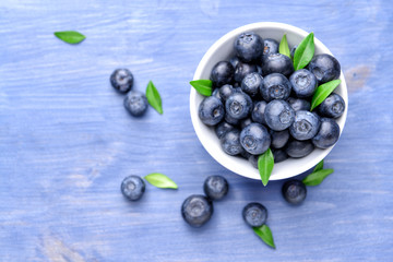 Bowl with ripe blueberry on wooden background