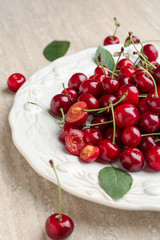 Plate with ripe cherry on table