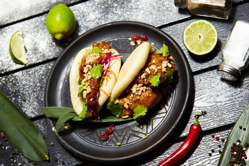Asian dish on a black plate. Bao with meat and vegetables