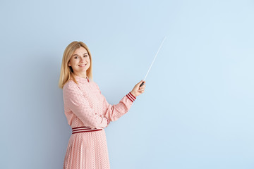 Beautiful female teacher with pointer on color background