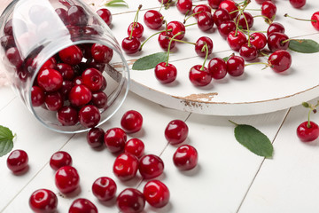 Scattered ripe cherry on white wooden background
