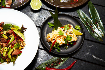 Asian dishes on a black table. Salads and snacks