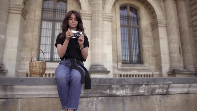 Beautiful young woman with dark hair, wearing jeans and black t-shirt is taking pictures of the city. Right to left pan real time wide shot