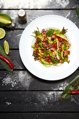 Asian dish on a white plate. Salad with roast duck, mango, avocado and sesame seeds