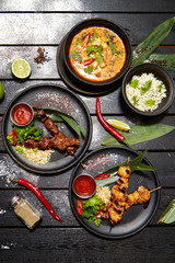 Asian dishes on a black table. Satay and Tom Yam
