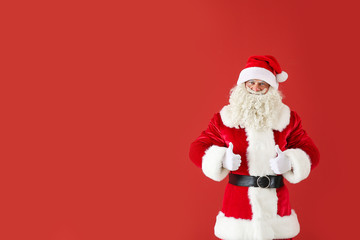 Fototapeta na wymiar Portrait of Santa Claus showing thumb-up on color background