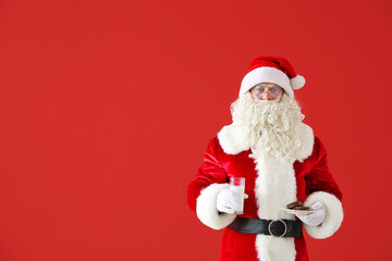 Santa Claus with milk and cookies on color background