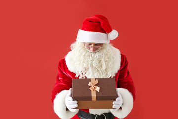 Portrait of Santa Claus with gift on color background