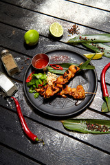 Asian dish on a black plate. Chicken Satay