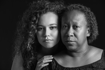 Black and white portrait of African-American woman with her daughter on dark background