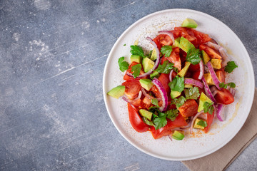 Fototapeta na wymiar Vegetarian salad with avocado, tomato and red onion. Top view, copy space