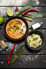 Asian dish on a black plate. Tom yum with rice