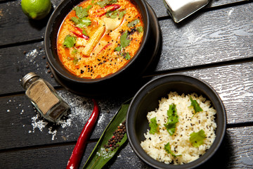 Asian dish on a black plate. Tom yum with rice