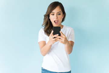 Surprised Female Using Smartphone Over Colored Background