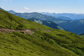 Fototapeta na wymiar Sunny mountain landscape with road on the slope