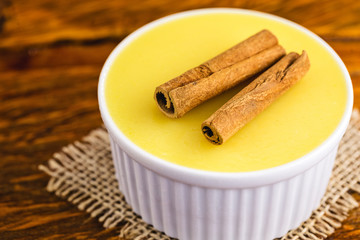 Typical Brazilian dessert, sweet of mingua, called in Brazil of curau. Typical sweet of June party. Brazilian sweet corn, corn mousse on a wooden background with copy space.