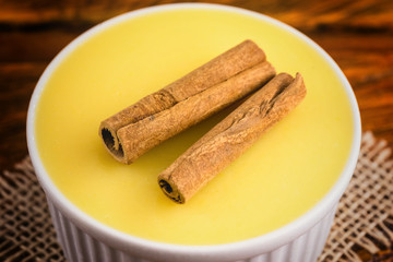 Typical Brazilian dessert, sweet of mingua, called in Brazil of curau. Typical sweet of June party. Brazilian sweet corn, corn mousse on a wooden background with copy space.