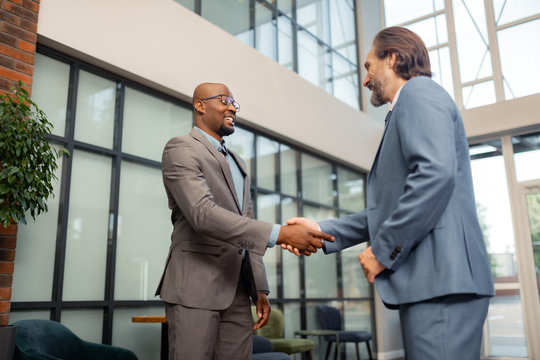 Businessman wearing glasses shaking hand of his investor