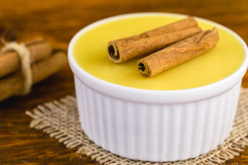 Brazilian sweet cream-like dessert cured corn mousse with cinnamon on a rustic wooden background.