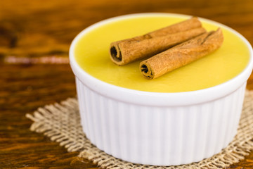 Brazilian sweet cream-like dessert cured corn mousse with cinnamon on a rustic wooden background.
