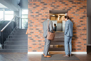Two prosperous businessmen entering lift in the business center