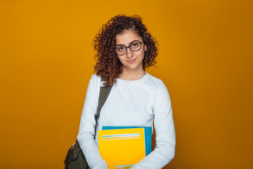 Portrait of a smiling Indian female student girl with books in glasses. Beautiful muslim mixed race...