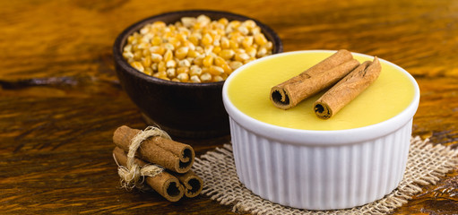Typical Brazilian dessert, sweet of mingua, called in Brazil of curau. Typical sweet of June party. Brazilian sweet corn, corn mousse on a wooden background with copy space.